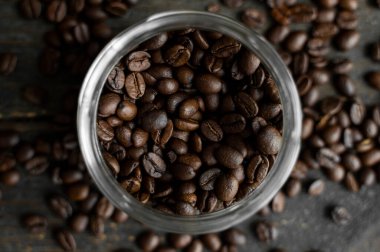 Tahta bir masada küçük bir kavanozda taze Arap kahve çekirdekleri. Taze kahve çekirdekleri masaya saçılmış..