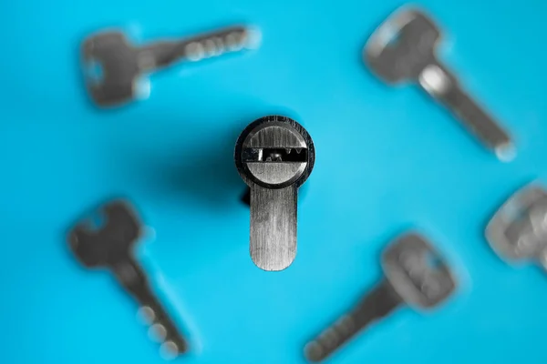 A door lock cylinder core with keys on the blue background. The cylinder of the lock with keys. Installing a new lock on the door. Spare parts for the door.