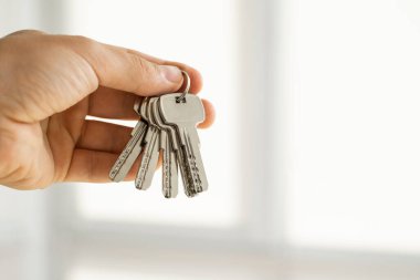 Erkeklerin elinde anahtarlar var. Emlakçı bir dairenin anahtarlarını müşterilerine veriyor. Anahtarlara odaklan. Emlakçıların elinde birkaç anahtar..