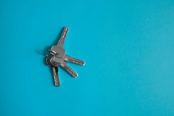 La clé de porte se trouve sur fond bleu. Ensemble de clés. Un paquet de clés. Clé de maison. Nouveau concept de maison. Location et vente. — Photo