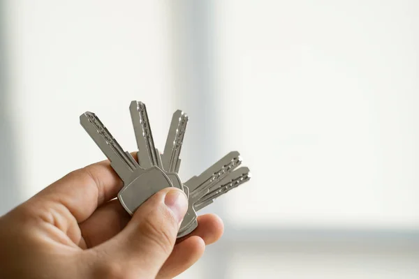 Manos de hombre sosteniendo un juego de llaves. Inmobiliaria está dando las llaves de un apartamento a los clientes. Concéntrate en las llaves. Manojo de llaves en una mano de los agentes inmobiliarios. —  Fotos de Stock