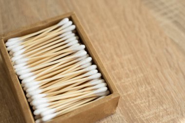 Çevre dostu pamuklu çubuklar. Masanın üzerinde geri dönüşümlü bambu tomurcukları olan bir karton kutu. Sıfır atık. Eko ürün. Kozmetik çubuklar kutuda. Kulakları temizlemek için tahta sopalar..