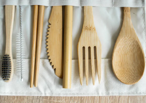 Masadaki bir kutuda, çevre dostu bambu çatal bıçak seti. Sıfır atık. Masanın üzerinde duran bir çantanın içindeki bambu çatal bıçak seti. Kaşık, çatal, bıçak, diş fırçası, tüp ve Çin çubukları..