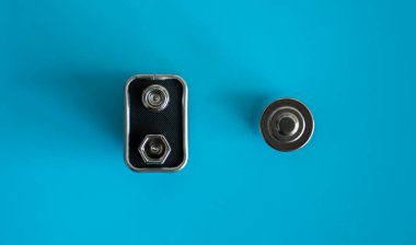 Yüksek voltajlı Volt 9V pil ve mavi arka planda alkali AA batarya. Enerji.