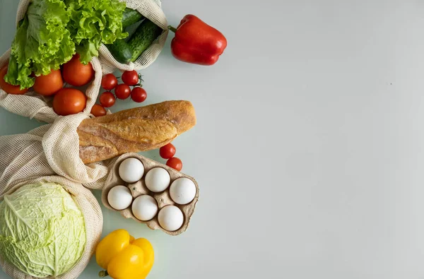 Vegetables, fruits, eggs in reusable eco cotton bags on table. Zero waste shopping concept. Plastic free items. Multi-use, reuse, recycle. Eco friendly canvas grocery bag with tomatoes, pepper, bread. — Stock Photo, Image