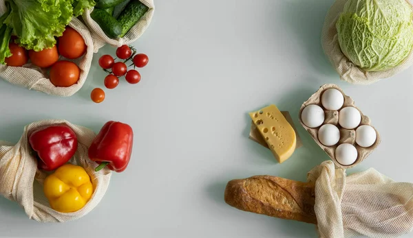 Vegetables, fruits, eggs in reusable eco cotton bags on table. Zero waste shopping concept. Plastic free items. Multi-use, reuse, recycle. Eco friendly canvas grocery bag with tomatoes, pepper, bread. — Stock Photo, Image