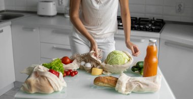 Yeniden kullanılabilir ekolojik market poşeti sebzeli ve lahanalı kadın elini tutuyor. Sıfır atık ve plastiksiz konsept. Kız elinde sebzeli pamuk alıcısı tutuyor..