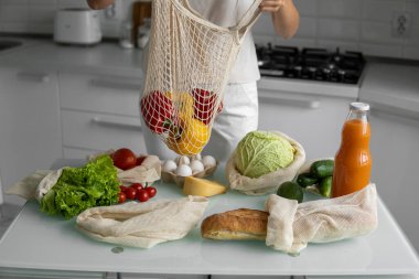 Yeniden kullanılabilir ekolojik markette sebzeli el ele tutuşan kadın kırmızı ve sarı biberi çıkardı. Sıfır atık ve plastiksiz konsept. Kız elinde sebzeli pamuk alıcısı tutuyor..