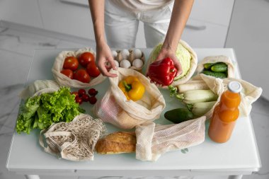 Yeniden kullanılabilir ekolojik markette sebzeli el ele tutuşan kadın kırmızı ve sarı biberi çıkardı. Sıfır atık ve plastiksiz konsept. Kız elinde sebzeli pamuk alıcısı tutuyor..
