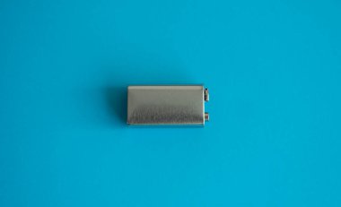 Mavi arka planda yüksek voltajlı pil. Gümüş Volt bataryası. 9V Gelişmiş Lityum Pilleri.