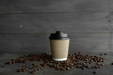 Ahşap masa arkasında kavrulmuş kahve çekirdekli kağıt kahve. Bir fincan sade kahve..