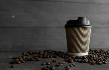 Ahşap masa arkasında kavrulmuş kahve çekirdekli kağıt kahve. Bir fincan sade kahve..