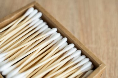 Çevre dostu pamuklu çubuklar. Masanın üzerinde geri dönüşümlü bambu tomurcukları olan bir karton kutu. Sıfır atık. Eko ürün. Kozmetik çubuklar kutuda. Kulakları temizlemek için tahta sopalar..