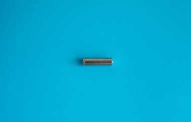 Mavi arka planda şarj edilebilir tek bir pil. Farklı cihazlar için gümüş alkali AA batarya. Enerji.