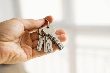 Erkeklerin elinde anahtarlar var. Emlakçı bir dairenin anahtarlarını müşterilerine veriyor. Anahtarlara odaklan. Emlakçıların elinde birkaç anahtar..