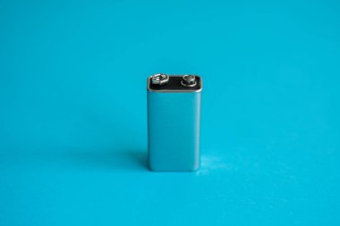 Mavi arka planda yüksek voltajlı pil. Gümüş Volt bataryası. 9V Gelişmiş Lityum Pilleri.