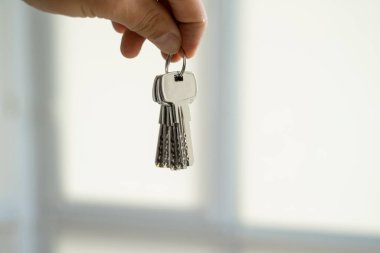 Erkeklerin elinde anahtarlar var. Emlakçı bir dairenin anahtarlarını müşterilerine veriyor. Anahtarlara odaklan. Emlakçıların elinde birkaç anahtar..