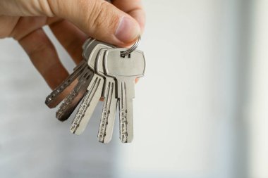 Erkeklerin elinde anahtarlar var. Emlakçı bir dairenin anahtarlarını müşterilerine veriyor. Anahtarlara odaklan. Emlakçıların elinde birkaç anahtar..