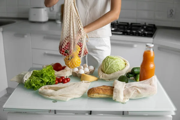 Kadın eli, evde sebzeli ve tekrar kullanılabilir bir market poşeti tutuyor ve biberi çıkarıyor. Sıfır atık ve plastiksiz konsept. Sebzeli pamuk satıcısı. Ekoloji.