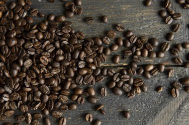 Ahşap bir masaya saçılmış kavrulmuş Arap kahve çekirdekleri. Taze kahve çekirdekleri.