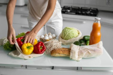 Kadın eli, evde sebzeli ve tekrar kullanılabilir bir market poşeti tutuyor ve biberi çıkarıyor. Sıfır atık ve plastiksiz konsept. Sebzeli pamuk satıcısı. Ekoloji.