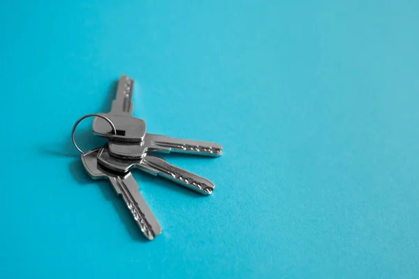 La clé de porte se trouve sur fond bleu. Ensemble de clés. Un paquet de clés. Clé de maison. Nouveau concept de maison. Location et vente. — Photo
