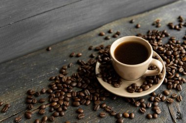 Ahşap masa arkasında kavrulmuş kahve çekirdekli kahve fincanı. Bir kupa sade kahve ve ahşap bir masanın üzerinde kahve çekirdekleri. Taze kahve çekirdekleri.