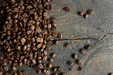 Ahşap bir masaya saçılmış kavrulmuş Arap kahve çekirdekleri. Taze kahve çekirdekleri.