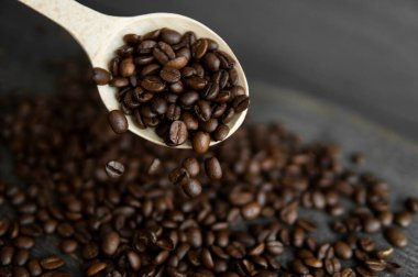 Ahşap bir masada meşe kaşığından düşen taze kavrulmuş Arap kahve çekirdekleri..