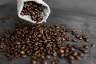 Kahve çekirdekleri ahşap bir masanın üzerindeki keten poşetinden yayılmış. Taze kavrulmuş Arap kahvesi..