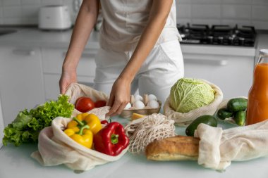 Kadın eli, evde sebzeli ve tekrar kullanılabilir bir market poşeti tutuyor ve biberi çıkarıyor. Sıfır atık ve plastiksiz konsept. Sebzeli pamuk satıcısı. Ekoloji.