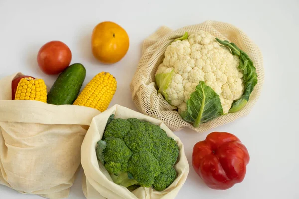 Vegetables in eco bag on white surface. Pepper, tomato, corn, cucumber, broccoli, cauliflower in reusable shopping eco friendly cotton fabric bags. Zero waste and plastic free concept. Sustainable. — Stock Photo, Image