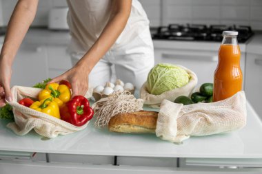 Kadın eli, evde sebzeli ve tekrar kullanılabilir bir market poşeti tutuyor ve biberi çıkarıyor. Sıfır atık ve plastiksiz konsept. Sebzeli pamuk satıcısı. Ekoloji.