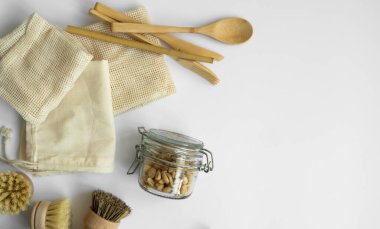 Sıfır atık. Çevre dostu bambu takımları ve temizlik fırçaları, ağ pamuk torbaları, cam kavanozlar, lif lifleri ve bir kutu pamuklu çubuk. Gri yüzeyde doğal ve yeniden kullanılabilir öğeler aksesuarları.