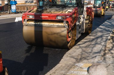 KYIV, UKRAINE - 10 Eylül 2020: Ağır asfalt yol silindirli ağır titreşimli paten sıkıştırıcısı, bir cadde üzerindeki yol inşaatında yeni bir sıcak asfalta baskı yapıyor..