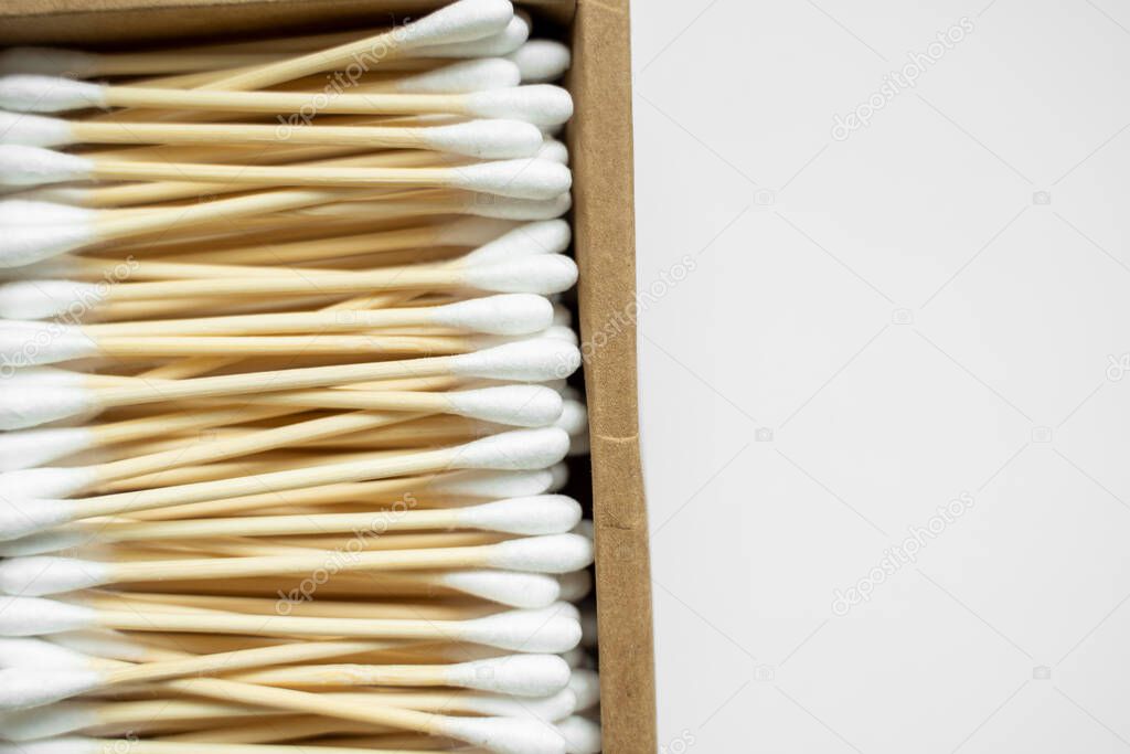 Eco-friendly cotton swabs. A cardboard box containing recyclable bamboo cotton buds on a gray surface. Zero waste concept. Eco product. Cosmetic sticks in a box. Wooden sticks for cleaning ears.