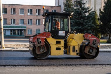 KYIV, UKRAINE - 10 Eylül 2020: Ağır asfalt yol silindirli ağır titreşimli paten sıkıştırıcısı, bir cadde üzerindeki yol inşaatında yeni bir sıcak asfalta baskı yapıyor..