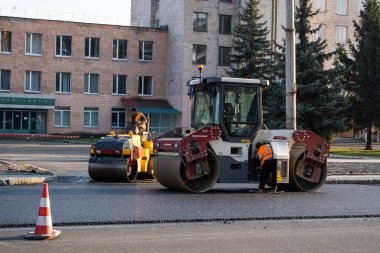 KYIV, UKRAINE - 10 Eylül 2020: Ağır asfalt yol silindirli ağır titreşimli paten sıkıştırıcısı, bir cadde üzerindeki yol inşaatında yeni bir sıcak asfalta baskı yapıyor..