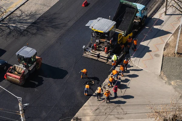 KYIV, UKRAINE - 10 september 2020: Tung asfalt vägvält med tung vibrationsvält komprimator som trycker ny varm asfalt och asfalt asfaltläggare maskin på en väg byggarbetsplats på en gata. — Stockfoto