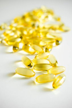 Beyaz arka plana saçılmış sarı omega-3 balık yağı kapsüllerinin yakın çekimi. Beslenme takviyeleri, sağlıklı beslenme, ilaç ve sağlık yaşam tarzı kavramı.