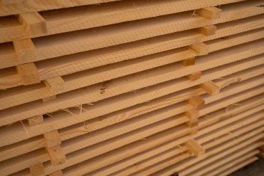 Yapım, marangozluk projeleri ve mobilya üretimi için ham kereste malzemesi sergilenen büyük bir yığın halinde istiflenmiş ahşap tahtaların yakın çekimi.