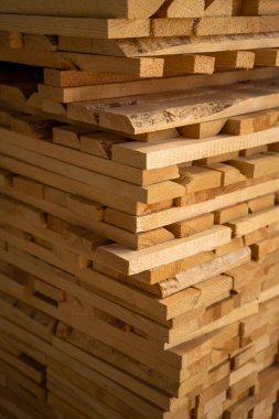 Yapım, marangozluk projeleri ve mobilya üretimi için ham kereste malzemesi sergilenen büyük bir yığın halinde istiflenmiş ahşap tahtaların yakın çekimi.