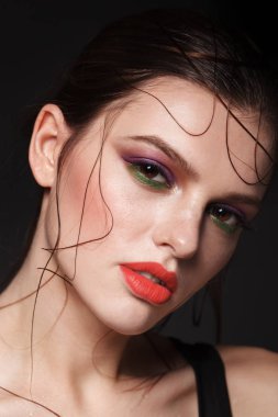 Esmer kırmızı dudaklar, yeşil göz kalemi ve ıslak saç modeliyle portresi