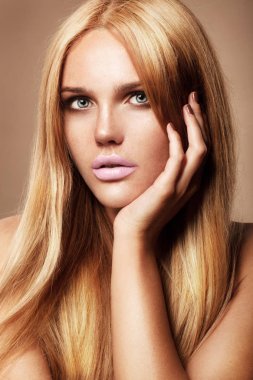 tabaklanmış sarışın model pembe dudakları yüzünü dokunaklı bej renkli arka plan üzerinde poz ile moda portre