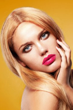 tabaklanmış sarışın model pembe dudakları yüzünü dokunaklı sarı arka plan üzerinde poz ile moda portre