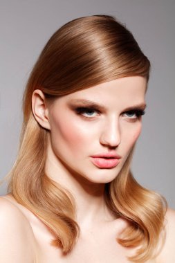 güzel makyaj ve saç gri arka plan üzerinde çıplak omuz ile poz çekici genç kadın