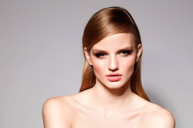 güzel makyaj ve saç gri arka plan üzerinde çıplak omuz ile poz çekici genç kadın