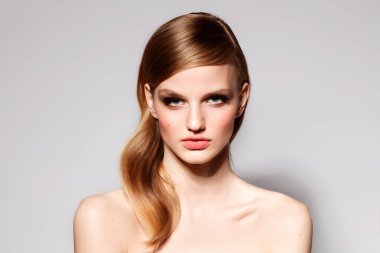 güzel makyaj ve saç gri arka plan üzerinde çıplak omuz ile poz çekici genç kadın