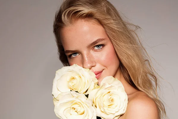 Beauty young model with white rose. Perfect glow skin. Blonde hair. Fresh look.