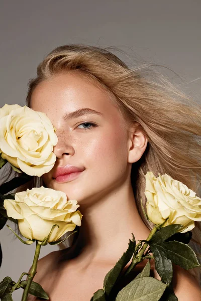 Beauty young model with white rose. Perfect glow skin. Blonde hair. Fresh look.